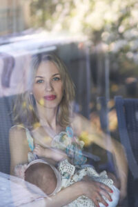 mother nursing child sitting on black wicker chair